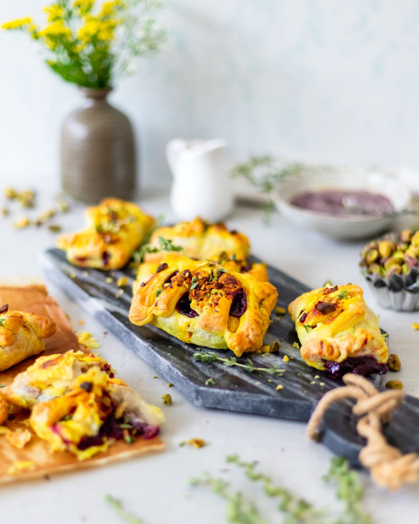 Golden Puff pastry pockets with a cherry filling. Topped with roasted pistachios, a turmeric glaze and fresh lemon thyme 