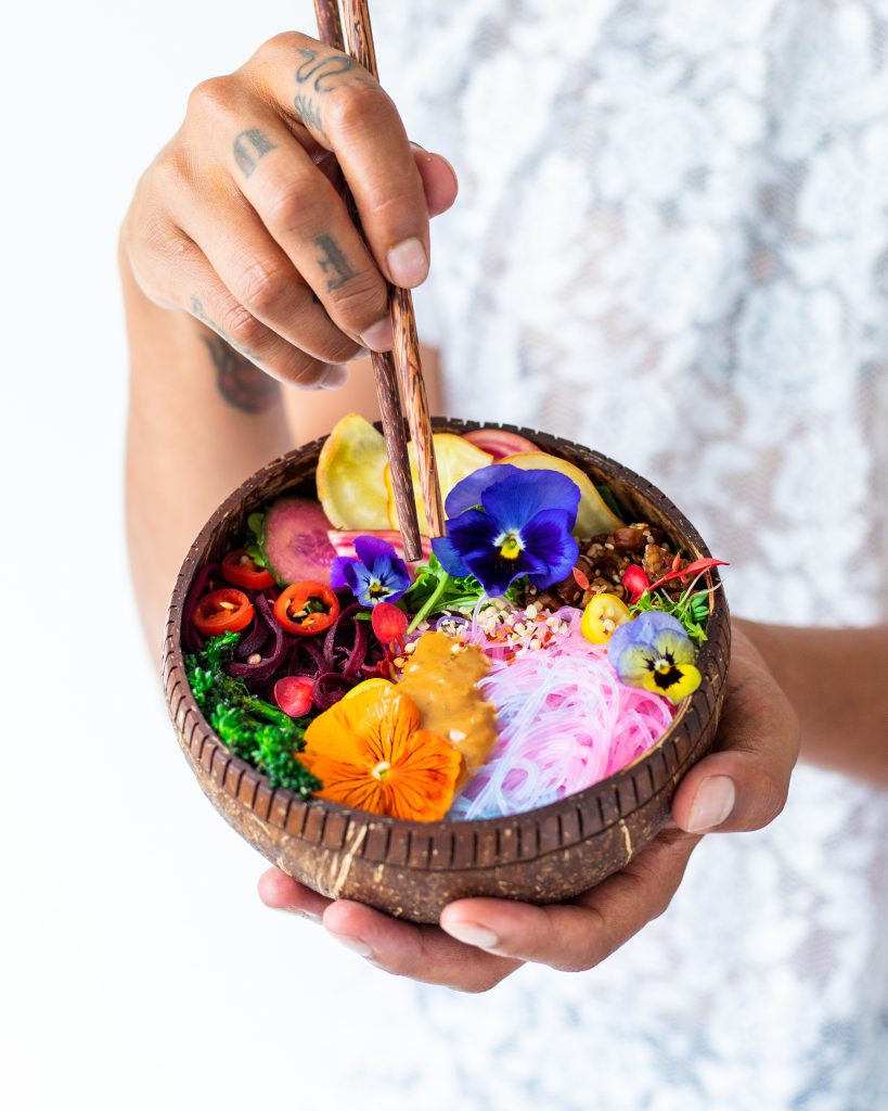 Jason holding up a coconut bowl filled with colourful food