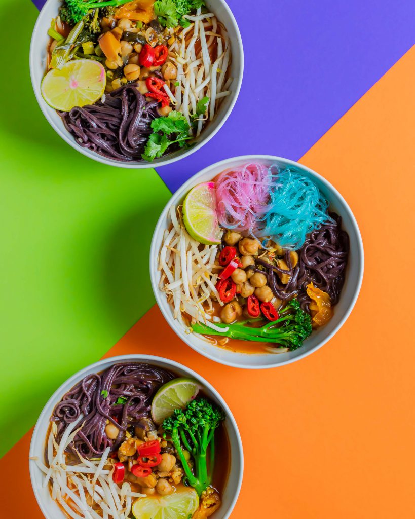 Three bowls containing the spicy soup, displayed on a colourful background.