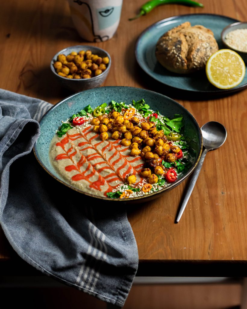 A bowl of celeriac soup served with chickpeas, peppers, herbs and bread