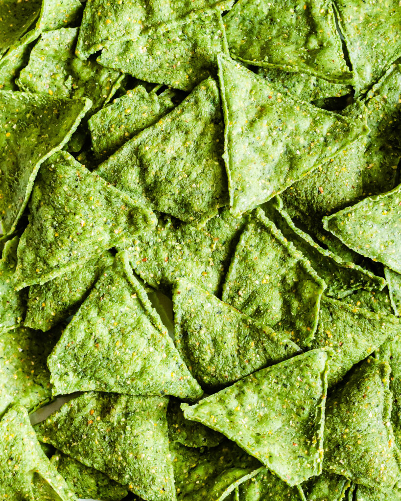 a close up of seaweed nachos. Due to the seaweed they have a vibrant green hue.