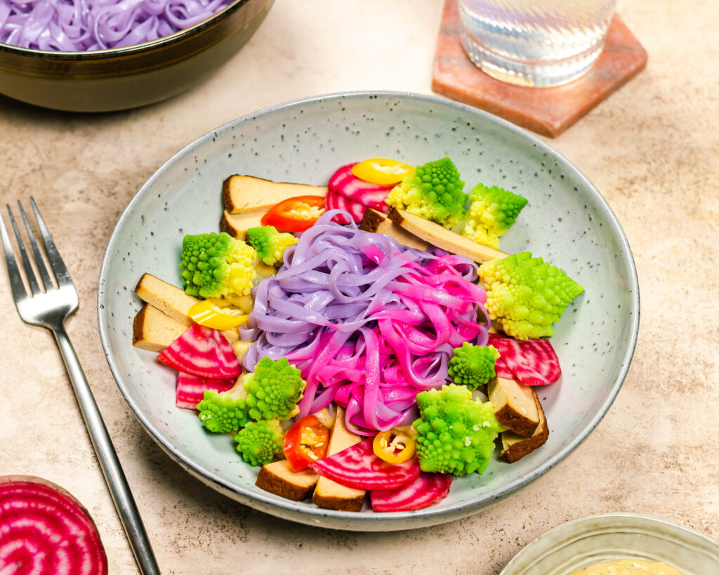 A bowl with colourful noodles, veggies and a creamy sauce