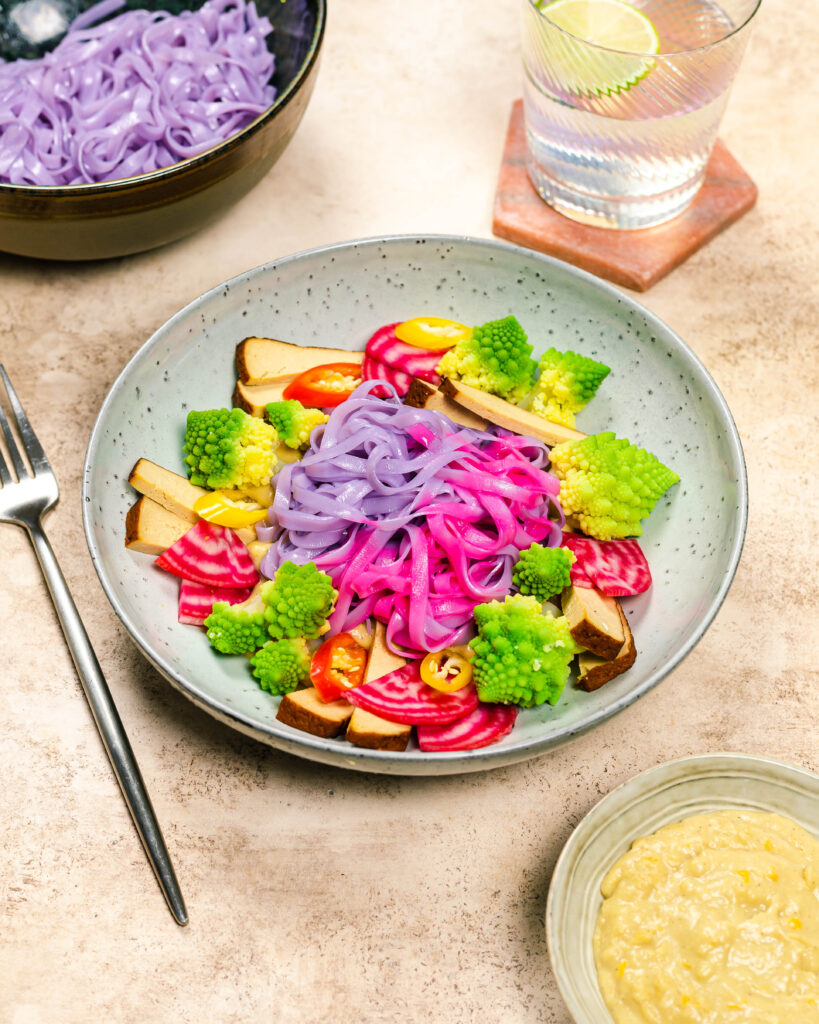 A bowl with colourful noodles, veggies and a creamy sauce
