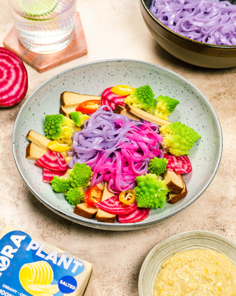 A bowl with colourful noodles, veggies and a creamy sauce